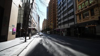 Merkez Sydney ana caddesi gün ışığında insanlar, araçlar ve dinamik hareketlerle yakalandı.