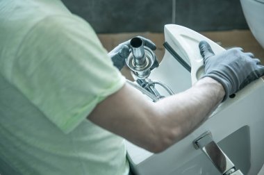 Tesisatçı yeni bir banyoya tuvalet kuruyor. Yeni bir ev konseptine geçiyoruz..