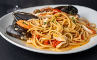 Siyah tabakta taze pişmiş makarna. Zarif yemek fotoğraflarında otlar ve malzemeler var..