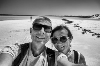 Gülümseyen turistler, berrak okyanus dalgaları ve tropikal palmiyeler vadisinde birlikte poz veriyorlar..