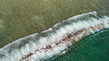 Ningaloo kıyısındaki istiridye yığınlarının turkuvaz suları ve kayalık oluşumlarıyla hava manzarası..