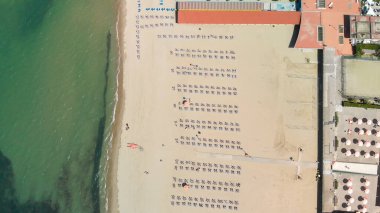 Renkli şemsiyeli ve yaz tatili atmosferli sahil beldesinin insansız hava aracı görüntüsü..