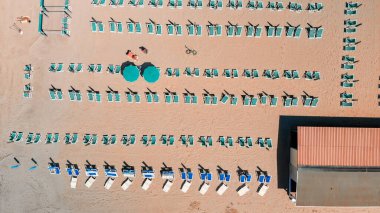 Renkli şemsiyeli ve yaz tatili atmosferli sahil beldesinin insansız hava aracı görüntüsü..