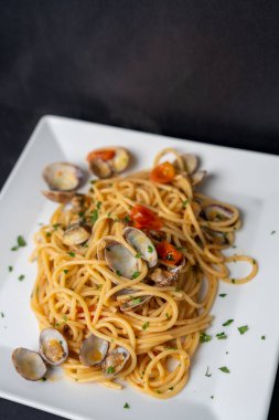 Siyah tabakta taze pişmiş makarna. Zarif yemek fotoğraflarında otlar ve malzemeler var..