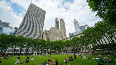New York Şehri - 12 Haziran 2025: Sıcak ve güneşli bir yaz gününde Bryant Park 'ta çimlerin üzerinde dinlenen turistler.