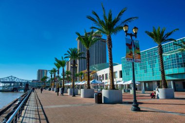 Güneşli gökyüzünün, kentsel çevrenin ve boş zamanların yer aldığı New Orleans 'ın manzaralı nehir kenarı..