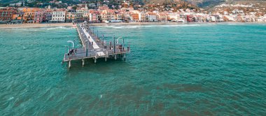 Spiaggia di Alassio 'nun turkuaz deniz ve kasaba manzaralı perspektifi.