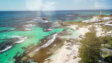Rottnest Adası sahil şeridinin panoramik manzarası berrak suları ve güneş ışığında el değmemiş plajı gösteriyor..