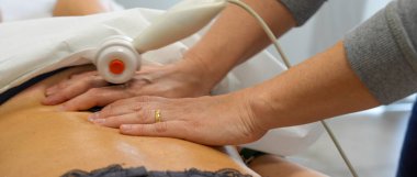 TECAR tedavisinin yakın çekimi fizyoterapi seansı sırasında bir kadının omzuna uygulanır.