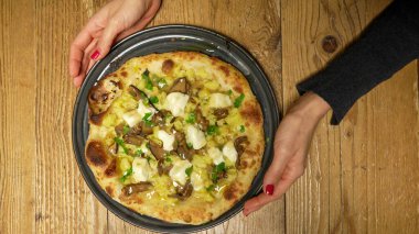 Lezzetli taze pişmiş pizza. Masada servis ediliyor. Soslar ve peynirle birlikte yemeye hazır..