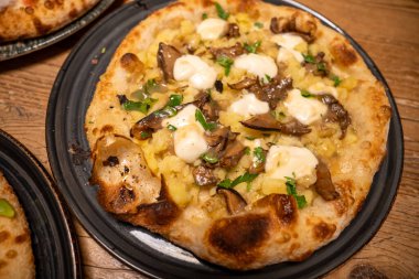 Lezzetli taze pişmiş pizza. Masada servis ediliyor. Soslar ve peynirle birlikte yemeye hazır..