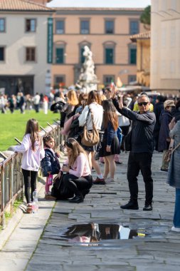 Pisa, İtalya - 20 Şubat 2026: Beyaz turistler Eğik Pisa Kulesi 'nin fotoğraflarını çekerken eğleniyorlar.