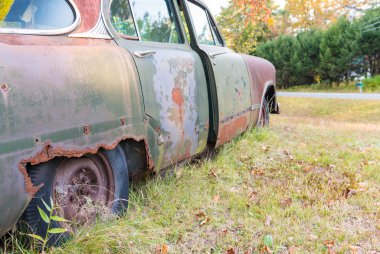 Eski araba çürüyen bir çayır ortasında terk edilmiş
