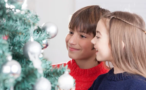 Мальчик и девочка украшают елку — стоковое фото