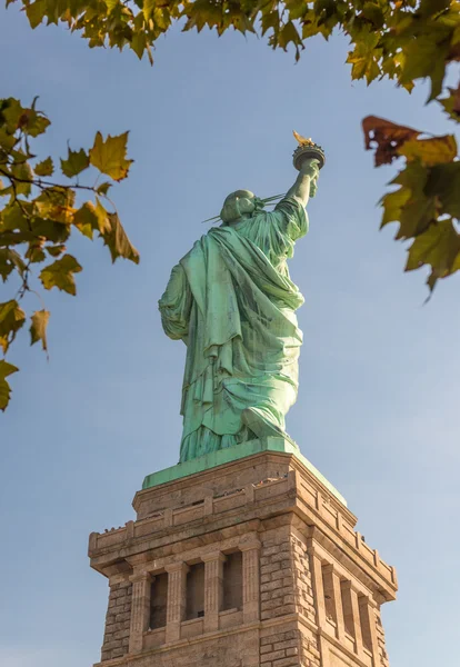 Vista traseira da Estátua da Liberdade cercada por árvores de outono — Fotografia de Stock