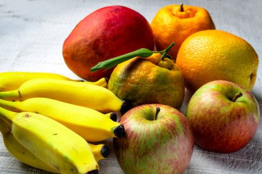 Masanın üzerinde beyaz masa örtüsü olan tropik meyve karışımı..