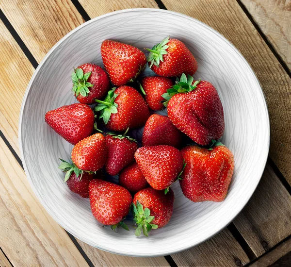 有木制背景的盘中美味的多汁草莓 — 图库照片