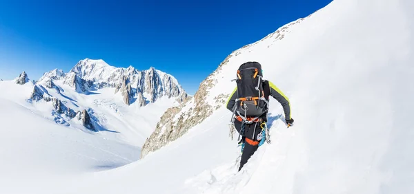 Mountaineer sobe um pico nevado. No fundo, os glaciares e o cume do Mont Blanc, a montanha europeia mais alta. Os Alpes, Chamonix, França, Europa . — Fotografia de Stock