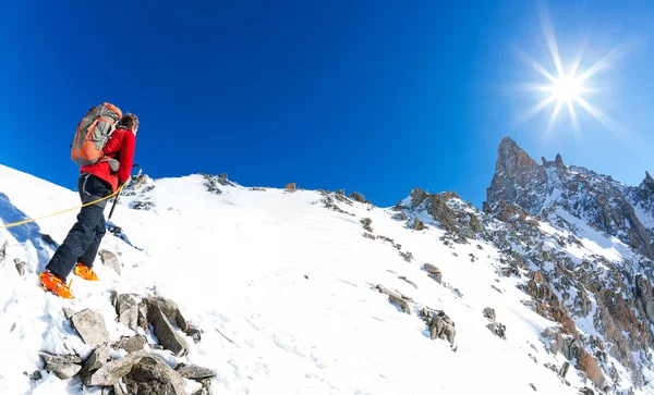 Alpinista wspina snowy szczyt. W tle słynnego szczytu Dent du Geant w masywie Mont Blanc, najwyższy szczyt Europy. Alpy, Chamonix, Francja, Europa. — Zdjęcie stockowe