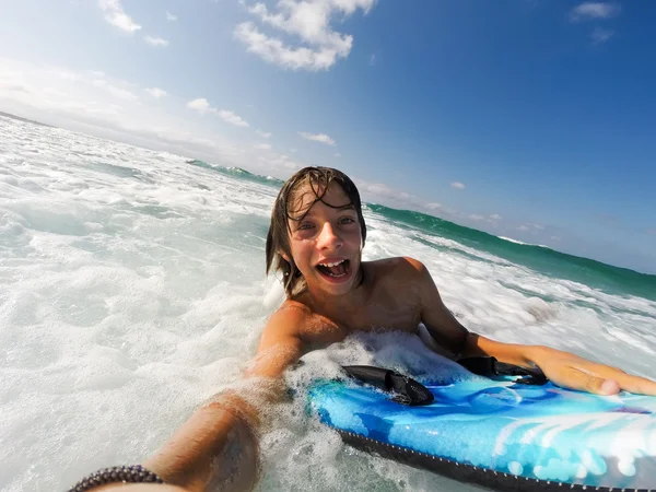 Chico disfruta montando las olas con una tabla de surf — Foto de Stock