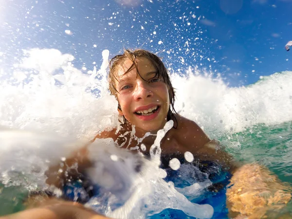 Menino gosta de andar nas ondas com uma prancha de surf — Fotografia de Stock