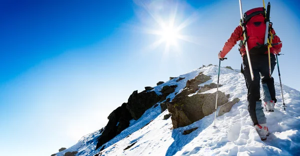 Alpinista de esqui caminhando ao longo de uma crista de neve íngreme — Fotografia de Stock