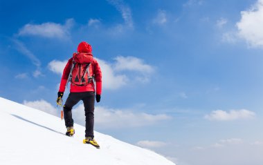 Mountaineer walking uphill along a snowy slope. clipart