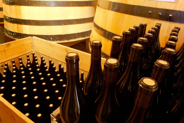 Rotweinflaschen mit Weinfässern im Hintergrund — Stockfoto