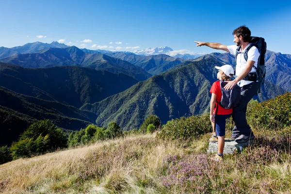 Mannen och unga boy stående i en berg äng — Stockfoto