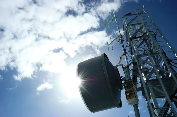 Torre de telecomunicaciones en contraluz contra un cielo azul nublado —  Fotos de Stock