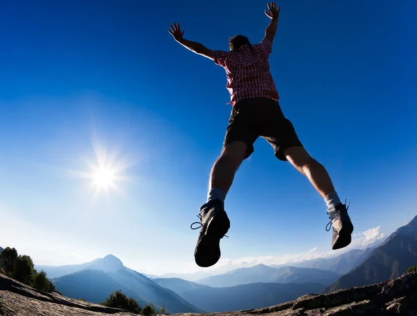 Mann springt bei Sonnenschein gegen blauen Himmel — Stockfoto