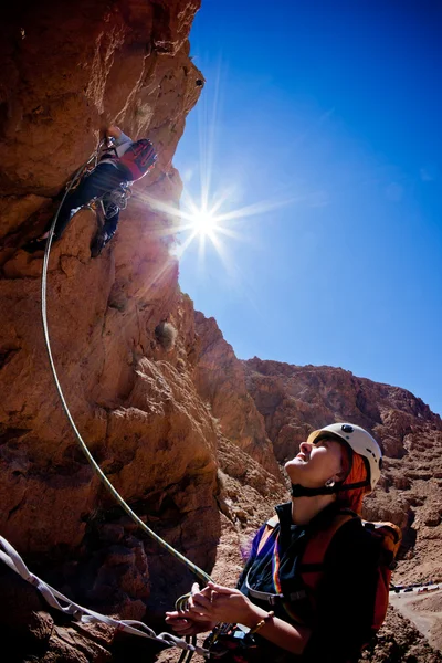 Bir kadın dağcı lideri belays — Stok fotoğraf
