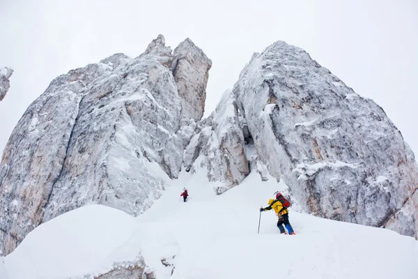 Zwei Bergsteiger nähern sich einer winterlichen Steilwand — Stockfoto