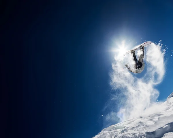 Masmavi gökyüzünde yüksek atlama yapmadan snowboarder