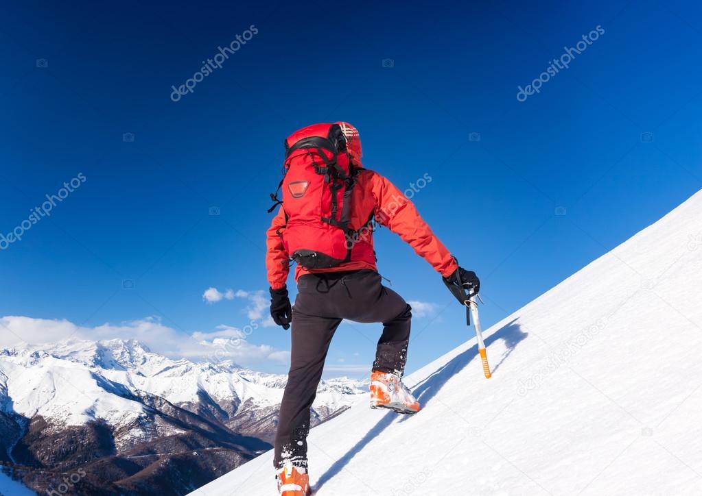 Climber walks up a snowy slope. Winter season, clear sky.