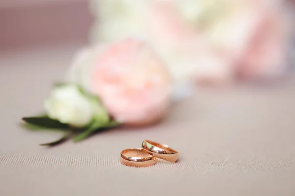 Dois anéis de casamento dourados em flores macro tiro — Fotografia de Stock