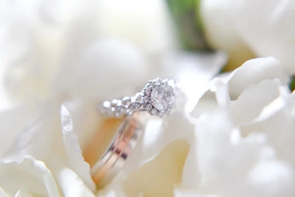 Due anelli da sposa dorati su macro shot di fiori — Foto Stock