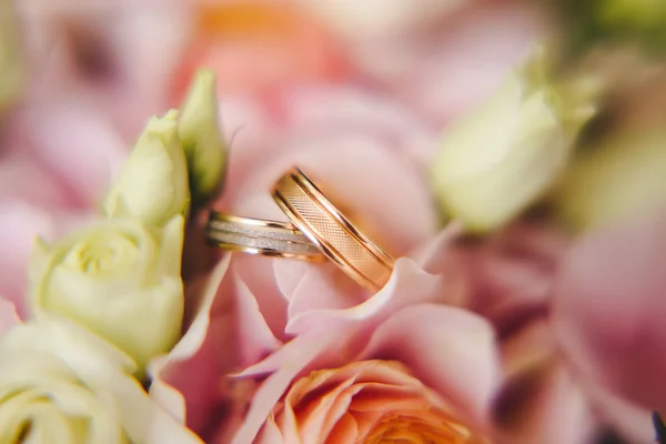 Dois anéis de casamento dourados em flores macro tiro — Fotografia de Stock