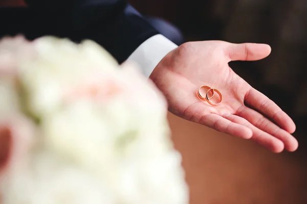 Anéis de casamento de ouro na palma do noivo — Fotografia de Stock
