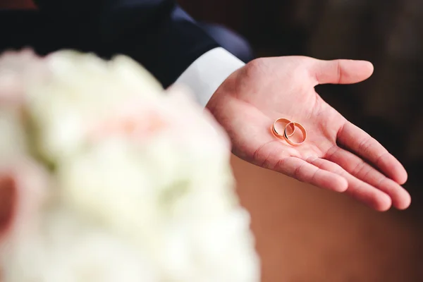 Anillos de boda de oro en la palma del novio — Foto de Stock