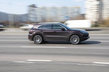 Ukrayna, Kyiv - 4 Nisan 2021: Kahverengi Porsche Cayenne arabası yolda ilerliyor. 