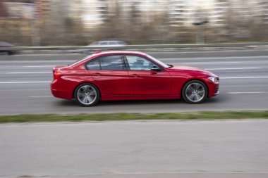 Ukrayna, Kyiv - 6 Nisan 2021: Kırmızı BMW 3 serisi araba yolda ilerliyor. 