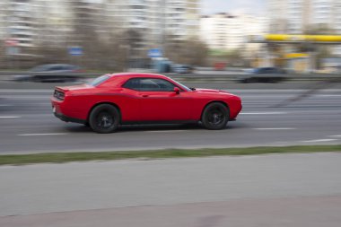 Ukrayna, Kyiv - 6 Nisan 2021: Kırmızı Dodge Challenger arabası yolda ilerliyor. 