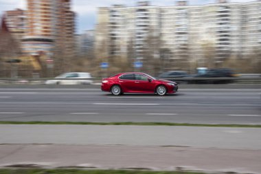 Ukrayna, Kyiv - 6 Nisan 2021: Kırmızı Toyota Camry arabası yolda ilerliyor.  