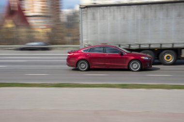 Ukrayna, Kyiv - 6 Nisan 2021: Kırmızı Ford Fusion (Kuzey Amerika) arabası yolda ilerliyor. 