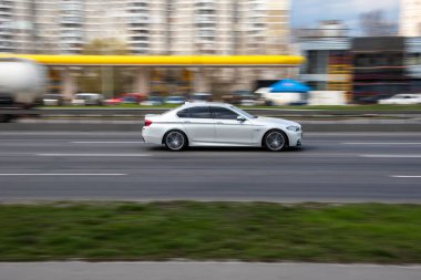 Ukrayna, Kyiv - 6 Nisan 2021: Beyaz BMW 5 Serisi araba yolda ilerliyor.  