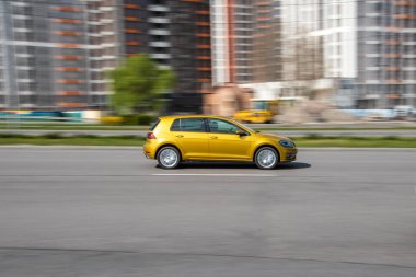 Ukrayna, Kyiv - 26 Nisan 2021: Turuncu Volkswagen Golf arabası yolda ilerliyor. Yazı