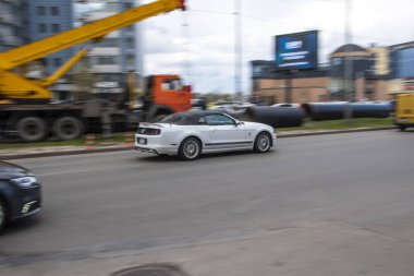 Ukrayna, Kyiv - 26 Nisan 2021: Beyaz Ford Mustang arabası sokakta hareket ediyor.  