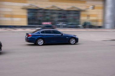 Ukrayna, Kyiv - 26 Nisan 2021: Mavi BMW 5 Serisi araba yolda ilerliyor. 