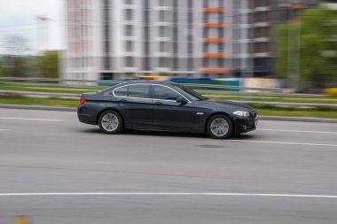 Ukrayna, Kyiv - 26 Nisan 2021: Siyah BMW 5 serisi araba sokakta hareket ediyor. Yazı